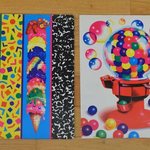 May include: Two notebooks with colorful designs. One features a tall ice cream cone with multiple scoops and a teddy bear on top. The other notebook has a gumball machine design with a clear globe filled with colorful gumballs.