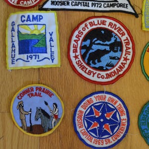 Peut inclure: Une collection de patchs brod&eacute;s color&eacute;s sur le th&egrave;me du camping et du scoutisme. Les patchs comportent des inscriptions telles que "Camp Gallahue Valley", "Bears of Blue River Trail", "Wyandotte Trail", "Conner Prairie Trail" et "Hoosier Capital 1969 Sr. Conference".