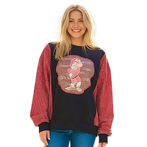 May include: Black sweatshirt with red and white checkered sleeves. The front features a cartoon image of Grumpy from Snow White, with text that reads "Grumpy Classic Origin 1937". The sweatshirt is a classic, casual style.