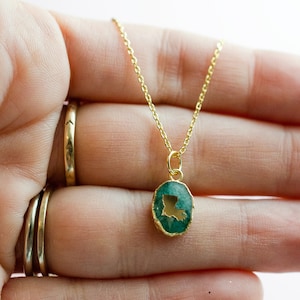 May include: A gold chain necklace with a green oval pendant featuring the outline of the state of Louisiana.