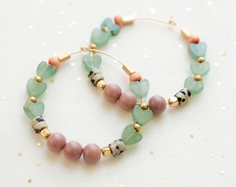 May include: Gold hoop earrings with green heart-shaped beads, pink beads, and speckled brown beads.