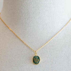 May include: A gold chain necklace with a green oval pendant featuring a gold snake design.