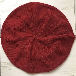 May include: A red knitted beret with a classic round shape.