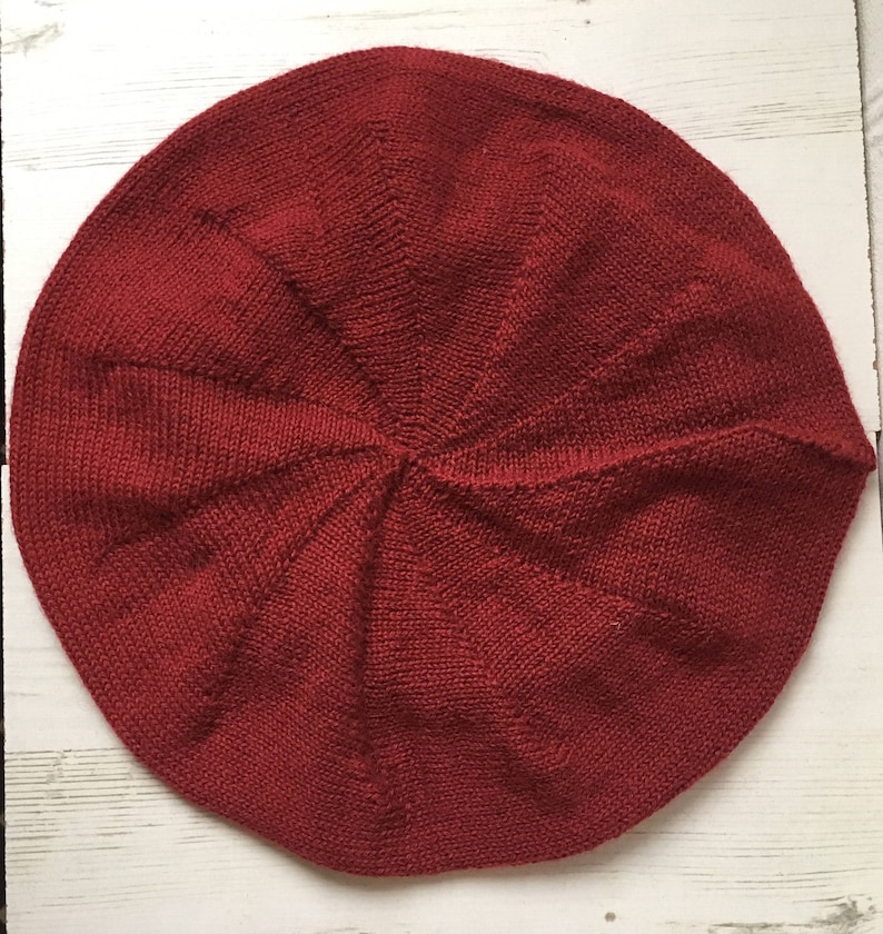 May include: A red knitted beret with a classic round shape.