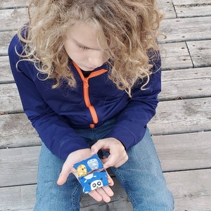 May include: Two small fabric pouches with animal designs. The pouches are open and show a panda, an owl, a lion, and a bear. The pouches are held in the hands of a person wearing blue jeans and a blue jacket.