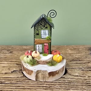 Pumpkin patch cottage. Little wooden house with pumpkins on a log slice. Autumn decor. Halloween decoration. Miniature pumpkin garden