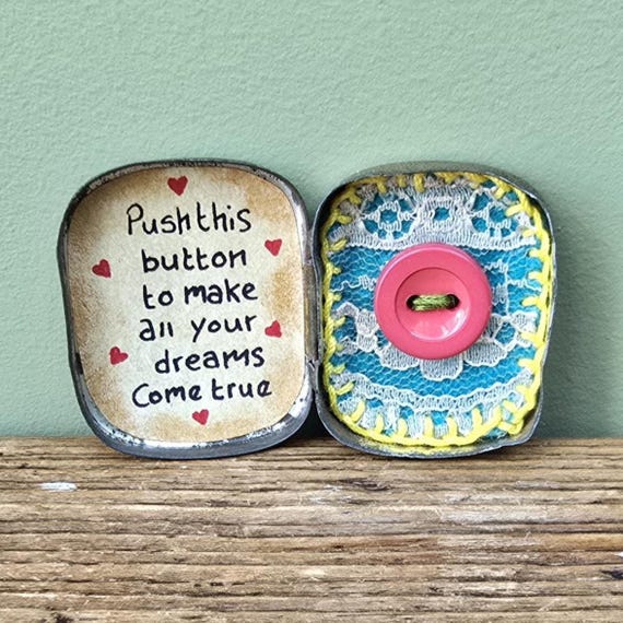 An upcycled vintage tin packed with recycled-fabric stuffing and a 'Magic Dreams Come True' button — a genuinely quirky, zero-waste handmade curiosity that feels like opening a tiny treasure chest.