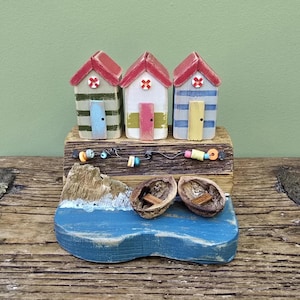 Wooden beach hut model. Colourful seaside beach huts made out of recycled wood with walnut shell boats. Miniature coastal diorama.