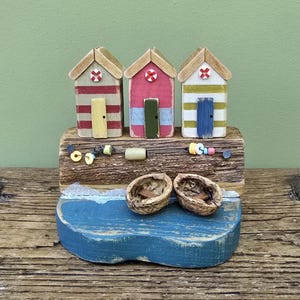 Wooden beach hut model. Colourful seaside beach huts made out of recycled wood with walnut shell boats. Miniature coastal diorama.
