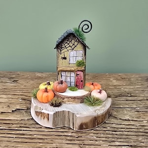 Pumpkin patch cottage. Little wooden house with pumpkins on a log slice. Autumn decor. Halloween decoration. Miniature pumpkin garden