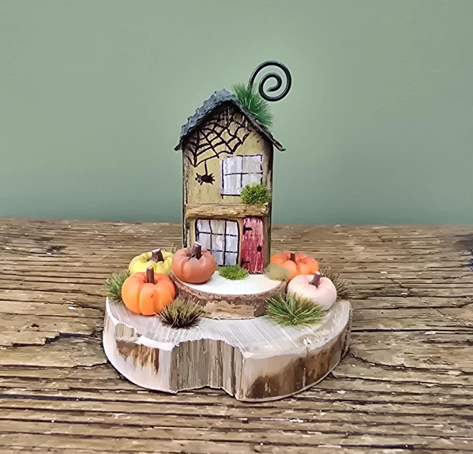 Pumpkin patch cottage. Little wooden house with pumpkins on a log slice. Autumn decor. Halloween decoration. Miniature pumpkin garden