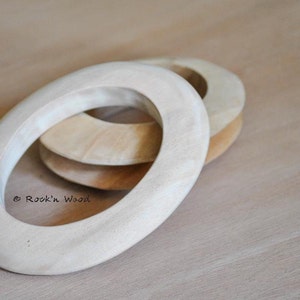 May include: Three unfinished wooden rings, stacked on top of each other. The rings are all the same size and shape, and they have a smooth, natural finish. The rings are a light brown color.