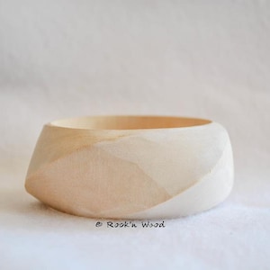 May include: A light wood bowl with a unique, geometric design. The bowl is smooth and has a natural, unfinished look.