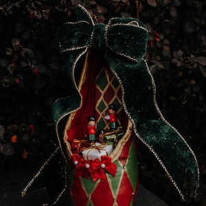 May include: A red and green ballet shoe with a green velvet bow. The shoe is filled with small gifts and toy soldiers.