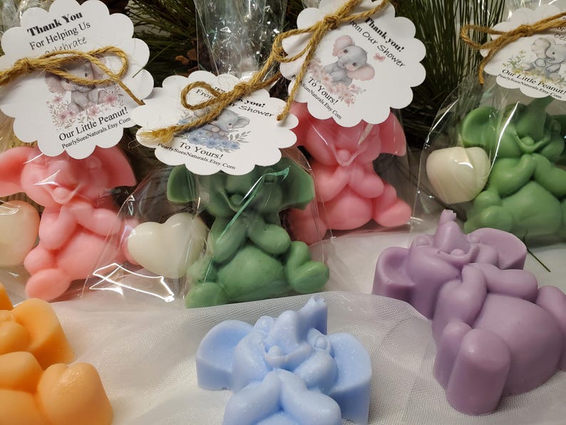 May include: An assortment of colorful elephant-shaped soaps in pink, green, purple, blue, and orange. Some are packaged in clear bags with decorative tags that read "Thank You" and "To Yours!" with a small elephant illustration.