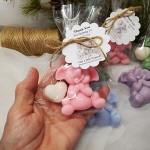 May include: Pink, purple, green, and blue elephant-shaped soaps, each holding a white heart. The soaps are packaged in clear cellophane bags, tied with twine, and adorned with a tag that reads "Our Little Peanut!"