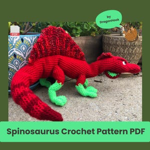 Op de afbeelding: Een rood en groen Spinosaurus haakpatroon PDF. De dinosaurus heeft een groot rood zeil, een lange staart en groene voeten. De tekst "Spinosaurus Crochet Pattern PDF" staat onderaan de afbeelding.