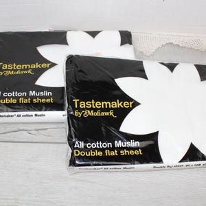 May include: Two packages of Tastemaker by Mohawk all cotton muslin double flat sheets. The black and white packaging features a large white flower graphic, yellow text, and the printed size of 81 x 108 inches before hemming on the front.