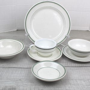 May include: A set of three ceramic mugs with a speckled, cream-colored glaze. Each mug features a different hand-painted floral design in shades of blue, green, and yellow. The mugs have a simple, modern shape.