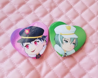 May include: Two heart-shaped pins featuring anime characters. The pin on the left has a pink background and features a character with black hair, wearing a black and red uniform and a black hat with a red star. The pin on the right has a green background and features a character with green hair, wearing a white hat with a gold badge and a white and blue uniform.