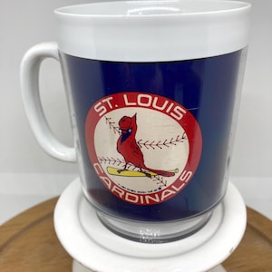 Op de afbeelding: Transparante mok met een witte handgreep en rand, met een marineblauwe body met het logo van het honkbalteam St. Louis Cardinals. Het logo bevat een rode kardinaalvogel en de woorden "St. Louis Cardinals".