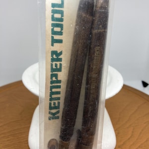 Puede incluir: Dos herramientas de cerámica de la marca Kemper Tools con mangos de madera son visibles a través de un embalaje transparente. Las herramientas son de color marrón oscuro. El embalaje tiene el logotipo de Kemper Tools en verde y blanco.