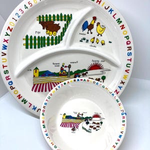 Puede incluir: Un plato dividido blanco y un cuenco a juego con una escena de granja colorida y el alfabeto y los números alrededor de los bordes. El plato presenta ilustraciones de cerdos, un gallo, pollitos y un sol poniente.