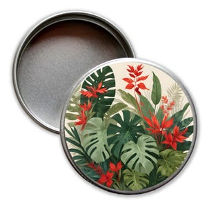 Könnte beinhalten: Eine runde Metalldose mit Deckel. Der Deckel hat ein Design aus tropischen Blättern und roten Blumen.