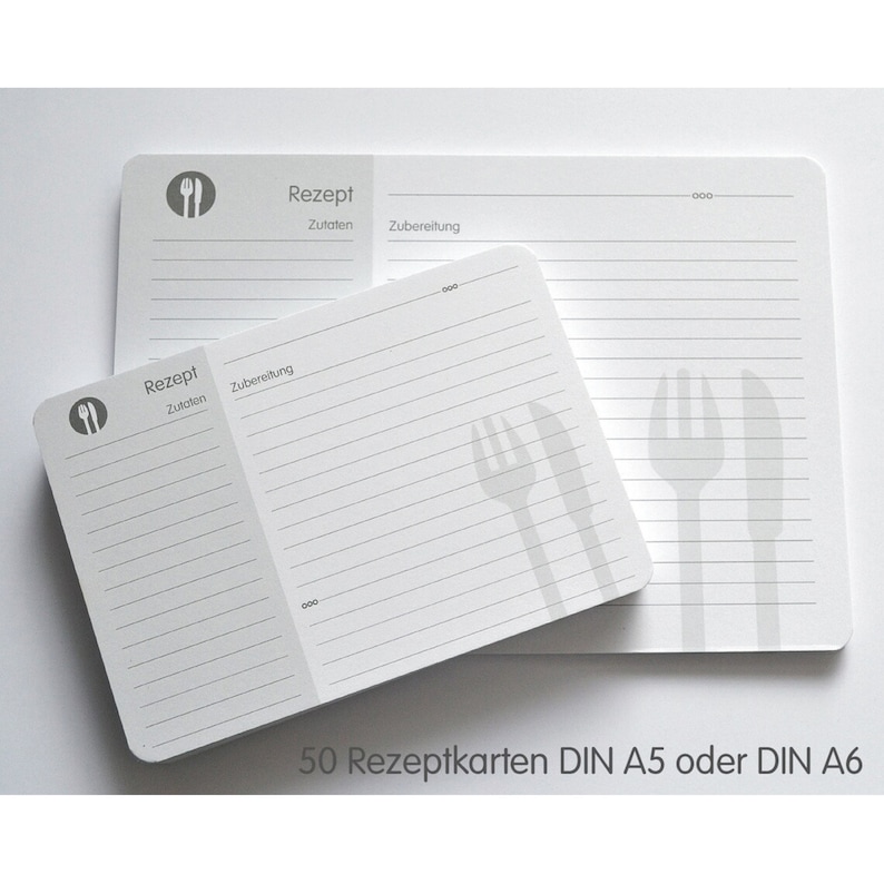 May include: A stack of 50 blank recipe cards in white with gray lines and a gray fork and knife icon. The text "Rezept" and "Zutaten" are printed on the cards. The text "50 Rezeptkarten DIN A5 oder DIN A6" is printed below the cards.