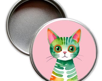 Puede incluir: Una lata redonda de metal con una tapa rosa. La tapa tiene una ilustración colorida de un gato rayado verde y naranja con ojos verdes.