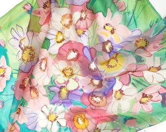 Könnte beinhalten: Ein Seidentuch mit einem Blumenmuster. Das Tuch ist grün, rosa und weiß mit einer Vielzahl von Blumen in verschiedenen Schattierungen von Rosa, Lila und Gelb.