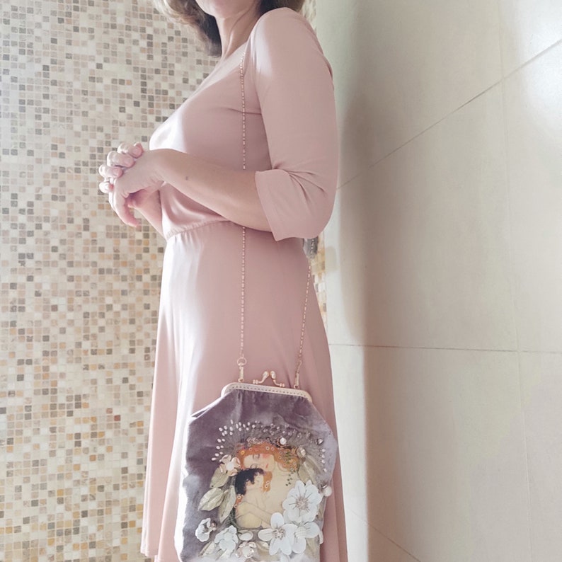 Puede incluir: Un vestido rosa claro con manga larga y un bolso de cadena a juego con un dise&ntilde;o floral y una imagen de inspiraci&oacute;n vintage.