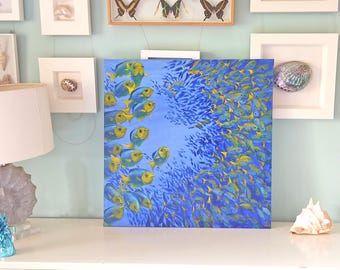 Puede incluir: Una pintura de una escuela de peces azules y amarillos nadando en un océano azul. Los peces están dispuestos en un patrón circular, con los peces más grandes en el centro y los peces más pequeños rodeándolos.