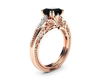 May include: A rose gold engagement ring with a black gemstone and small diamonds set in a filigree design.