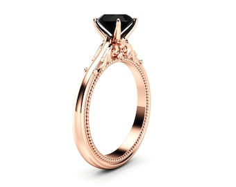 May include: Rose gold ring featuring a large, square-cut black gemstone. The band has a detailed, ornate design with a beaded edge. The ring is set against a white background, highlighting its elegant features.