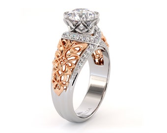 May include: A white gold and rose gold engagement ring with a large, round, clear center stone and smaller clear stones set in a delicate filigree design. The ring is engraved with the word "ELLA".