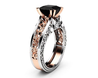 May include: A black diamond engagement ring with a rose gold and white gold band. The band is adorned with intricate floral designs.
