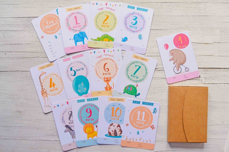 May include: A set of 11 baby milestone cards with colorful illustrations of animals and the text "Oggi Compio" (meaning "Today I Turn") in Italian. The cards are numbered 1 through 11, representing each month of the baby's first year.