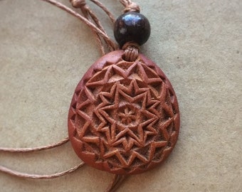 Carved avocado pit necklace. Geometric design with a flower. Chipcarving.