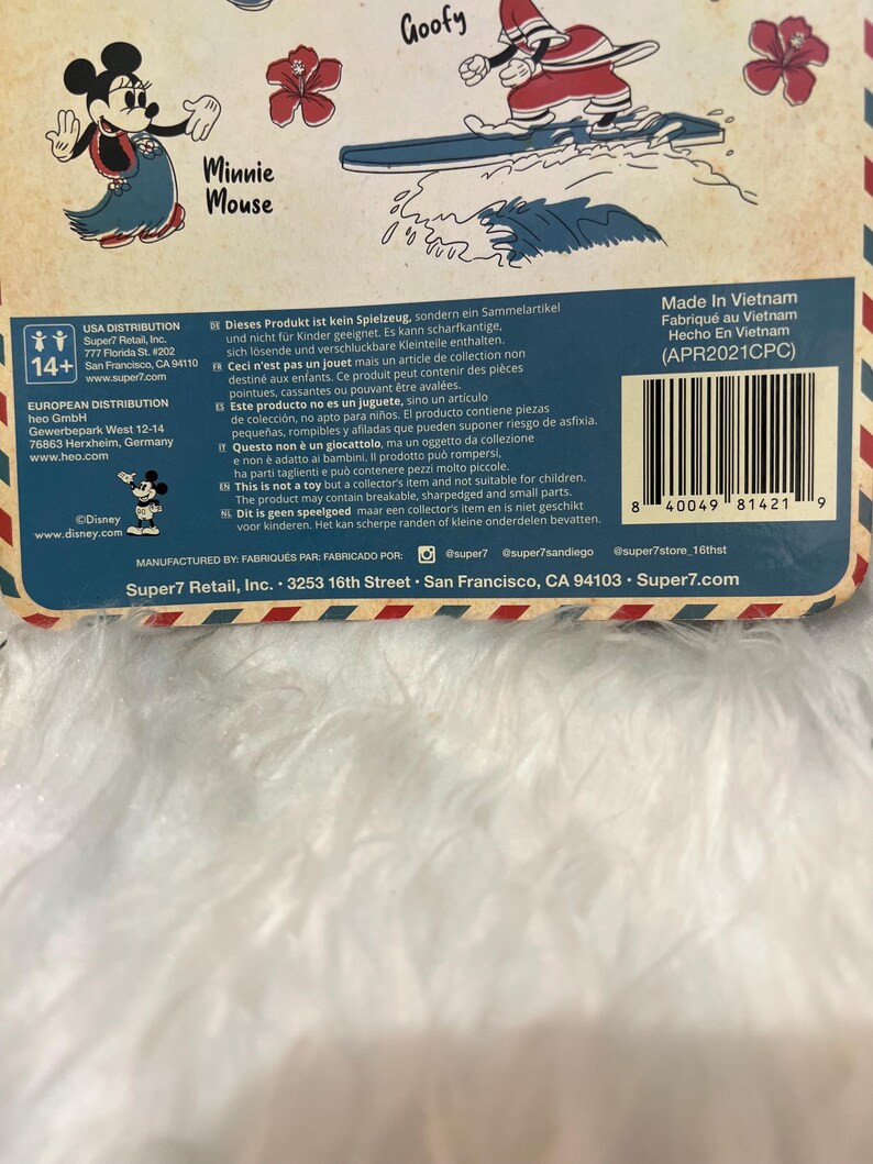 May include: A product package featuring illustrations of Disney characters Minnie Mouse and Goofy. The package includes text in multiple languages, warnings, and a barcode. The product is manufactured by Super7 Retail, Inc.