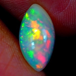 May include: A vibrant, iridescent opal gemstone with a teardrop shape. The opal displays a range of colors, including green, yellow, orange, and pink.