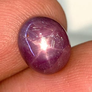 Op de afbeelding: Een cabochon geslepen, paarse ster-robijn edelsteen met een zespuntige ster.