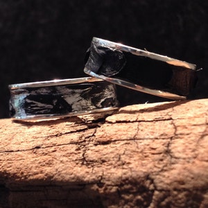 May include: Two silver rings with black and white patterned inlays. The rings are stacked on top of each other.