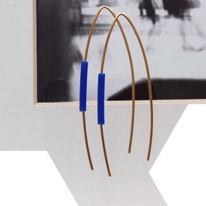 Op de afbeelding: Een paar gouden creolen met blauwe accenten. De creolen zijn dun en delicaat, en de blauwe accenten zijn klein en rechthoekig.