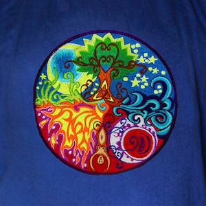May include: A royal blue t-shirt featuring a colourful embroidered design of a tree of life surrounded by four elements: earth, fire, water, and air.