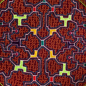 Pode incluir: Uma tapeçaria circular tecida à mão com um desenho geométrico em tons de vermelho, laranja, amarelo, verde e azul. A tapeçaria é cercada por uma borda amarela e laranja.