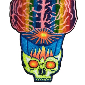 May include: Embroidered patch featuring a colorful brain design with rainbow stripes, a blue geometric shape, and a neon green skull with orange eyes. The patch has a black border and is likely for clothing or accessories.