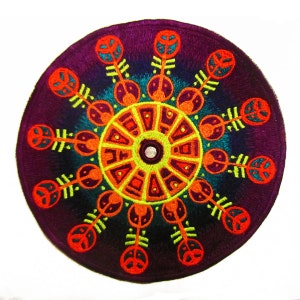 Könnte beinhalten: Runder, gestickter Aufnäher mit einem lebendigen, symmetrischen Design. Der Aufnäher hat einen tiefvioletten Hintergrund mit einem zentralen Sonnenmuster in Orange, Gelb und Türkis. Das Design umfasst stilisierte Blatt- und Peace-Zeichen-Motive.