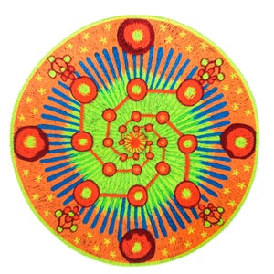 Op de afbeelding: Ronde geborduurde patch met een levendig geometrisch ontwerp. De patch heeft een helderoranje rand met kleine gele stervormige vormen. Binnenin wordt een groen en oranje spiraalpatroon geaccentueerd met blauwe lijnen en rode cirkels.