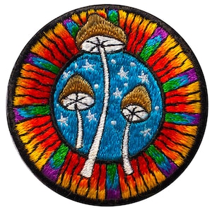 Peut inclure: Écusson brodé représentant trois champignons stylisés avec des chapeaux bruns et des tiges blanches sur un fond bleu étoilé. L'écusson est entouré d'une bordure aux couleurs de l'arc-en-ciel et d'un bord noir.